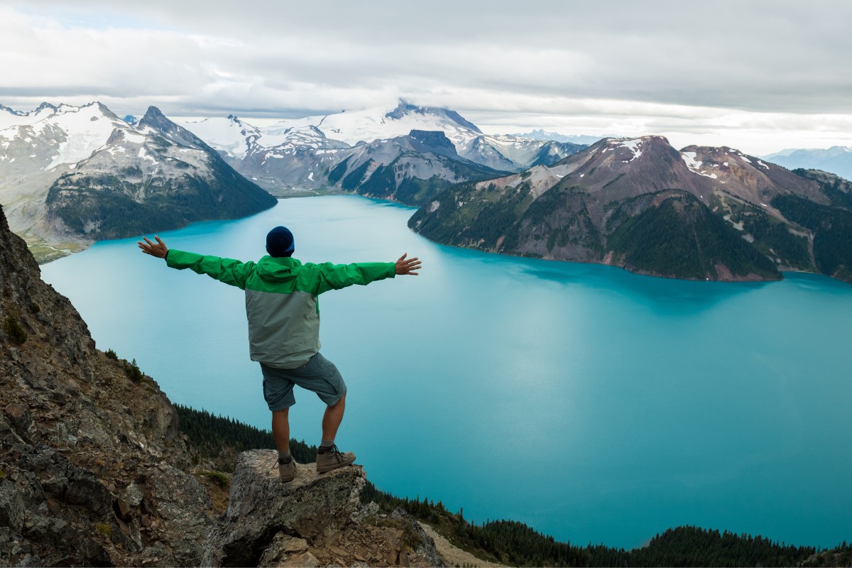 man on top of mountain overlooking a lake